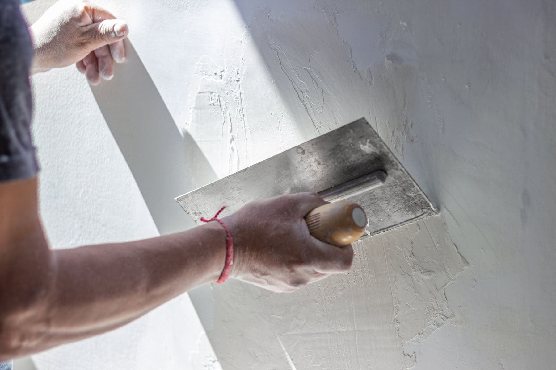 A plasterer smoothing a wall with a trowel.